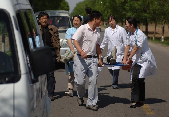 5月12日,陕西省旬邑县震感强烈,一名因地震造成水塔倒塌而受伤的人员被医护人员抬上救护车。 据国家地震台网重新核定,北京时间5月12日14时28分,在四川汶川县发生的地震震级为7.8级。新华社记者丁海涛摄