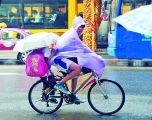 昨日下午,广州市区继续下雨,有学生家长骑单车冒雨接孩子回家.