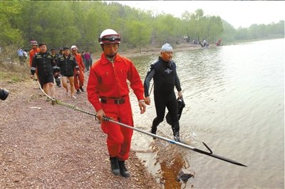 消防队员带着打捞钩进入水域.