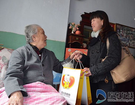 婴儿乐公益之旅走进大海阳社区 山东婴儿乐股份有限公司工会主席刘卫红将慰问品交给老人
