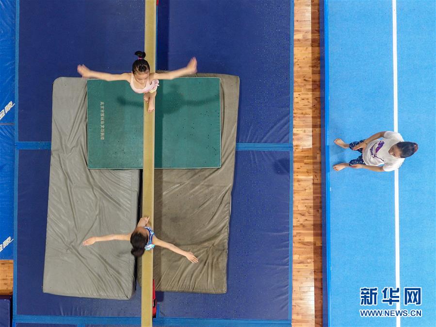 图为小学员徐子涵(左上)在榕江县少年儿童业余体操运动学校内进行平衡木训练(5月15日摄)。 新华社记者刘续摄