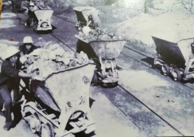 战士们把坑道里的石渣装入轱辘马车,沿简易滑道推出坑道倒掉