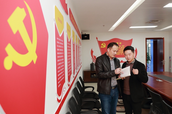 图为张传钦(左一)与同事一起探讨党支部建设