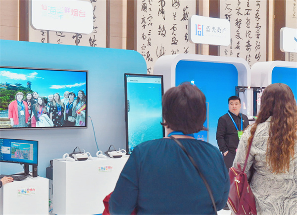 中外参会嘉宾在烟台文旅云展台前,体验智能魔镜功能,纷纷在烟台网红地云端打卡留念 1