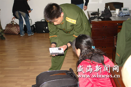 图为4月10日边防官兵在查获部分涉案人员后,对其证件进行检查.