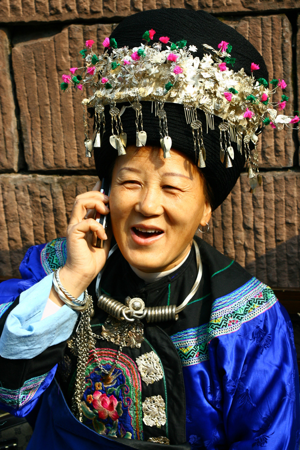 我旅游至凤凰古城,看到城墙外坐着的苗族老妇人