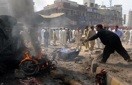 图为一名巴基斯坦市民试图用沙子扑灭燃烧的摩托车.