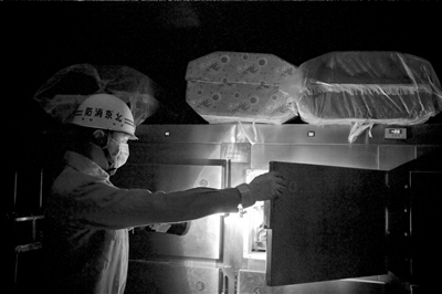 在漆黑的太平间,消防队员打开停尸柜观察尸体.