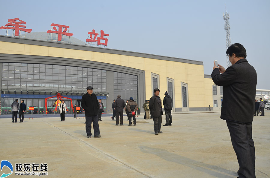 老人在牟平站前广场拍照留念