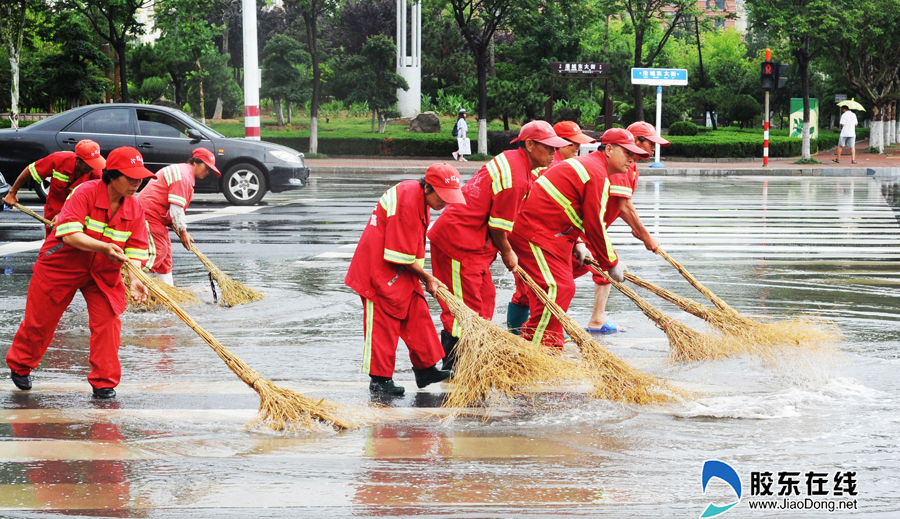 保洁人员正在迎春大街与港城东大街交汇处清扫道路积水