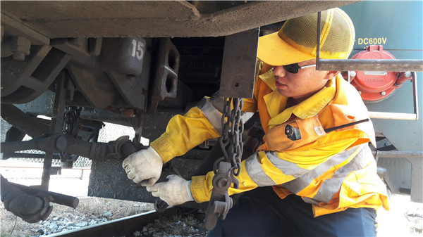 连接员刘佳车底摘解制动软管进行车辆解体.