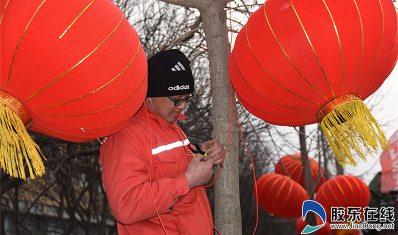 景观施工人员在莱山区宝源路安装大红灯笼