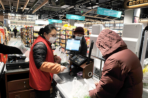 金茂超市工作人员正在使用烟台农商银行提供的智慧收银系统为市民服务